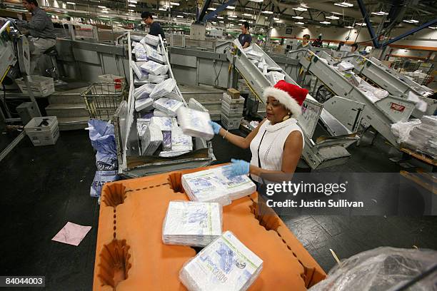 Postal worker Deborah Miller throws packages of magazines onto a conveyor belt at the U.S. Post Office sort center December 15, 2008 in San...