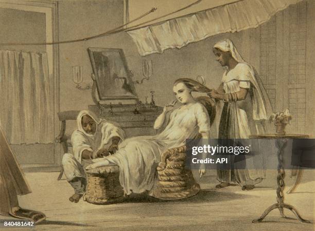 Femme d'un colon britannique se faisant masser les pieds et coiffer par des domestiques en Inde, en 1860.