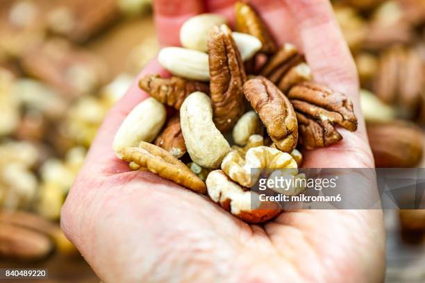 woman holding handful of fresh nuts. mixed whole nuts. nut sources of vitamin b9 folate - mature adult foto e immagini stock