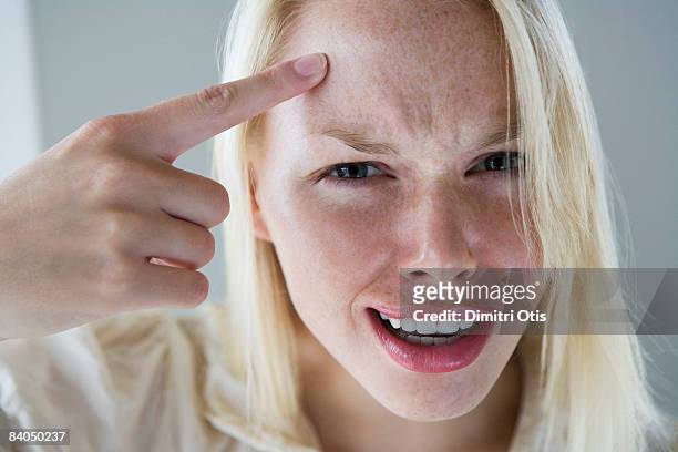 girl taping her forehead "are you crazy" - tapping points stockfoto's en -beelden