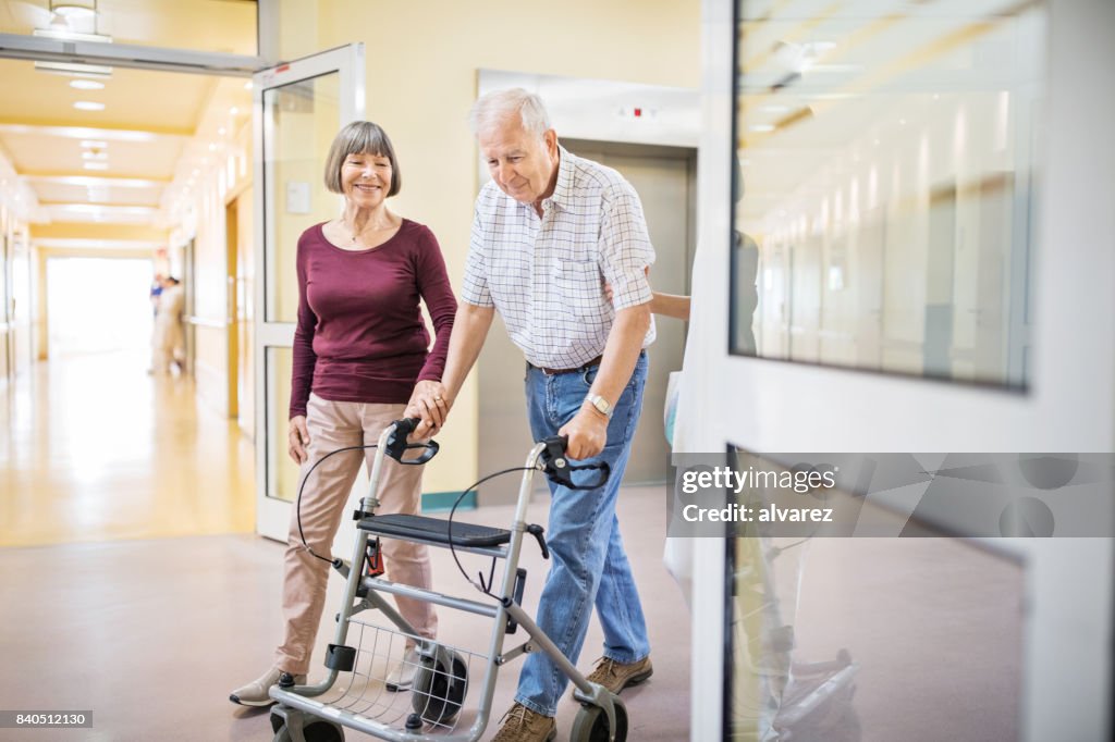 Senior woman helping man with walking frame