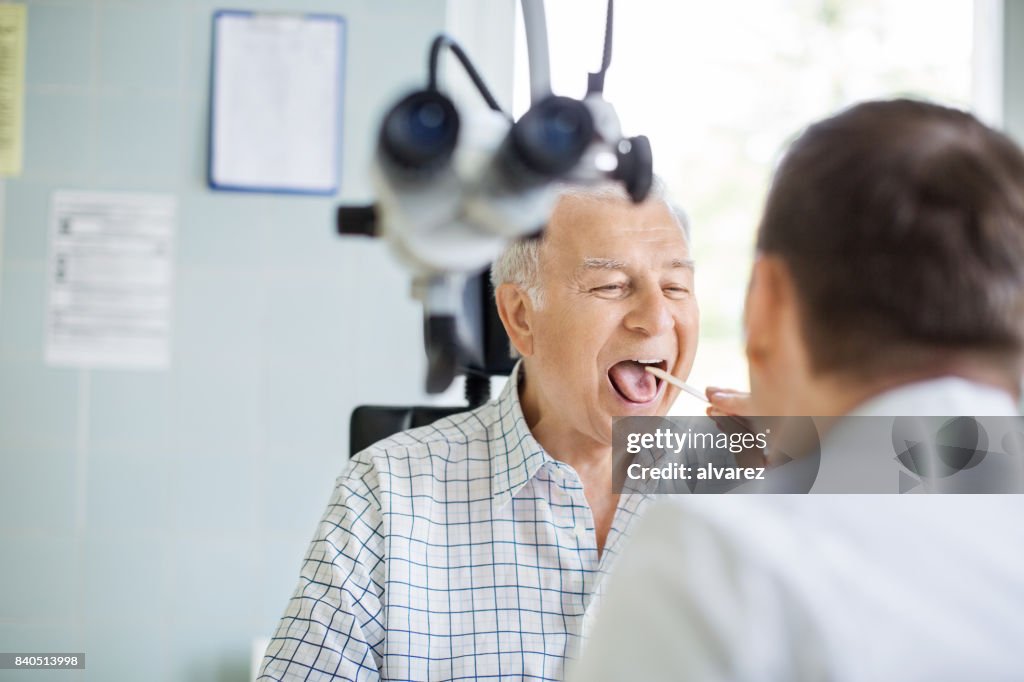 Médico examina la garganta del paciente mayor