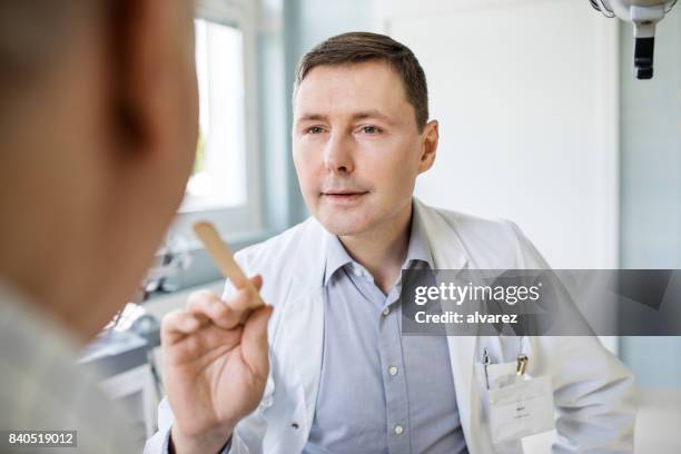 otolaryngologist examines sore throat of patient - tongue depressor stock pictures, royalty-free photos & images