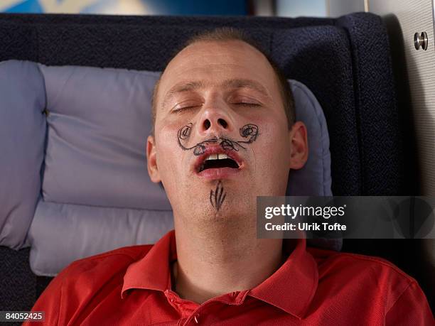 sleeping man with drawn moustache - moustaches stockfoto's en -beelden