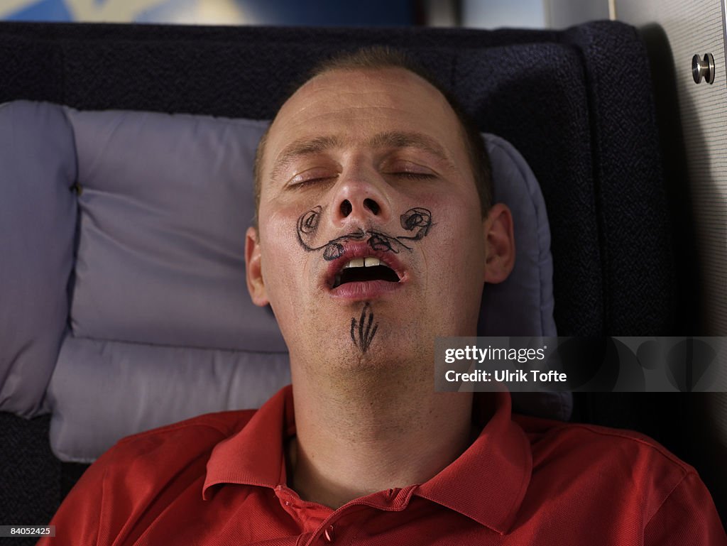 Sleeping man with drawn moustache