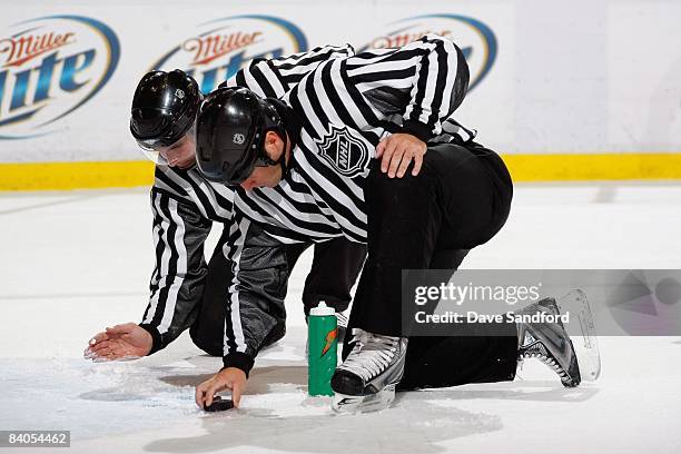 Linesmen Steve Miller and Jonny Murray repair the ice during the Detroit Red Wings game against the Calgary Flames at Joe Louis Arena December on 10,...