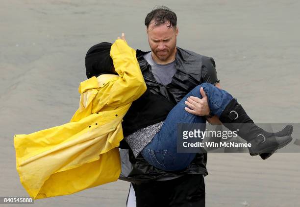 Volunteer carries a woman whose home was impacted by severe flooding following Hurricane Harvey in north Houston August 29, 2017 in Houston, Texas....