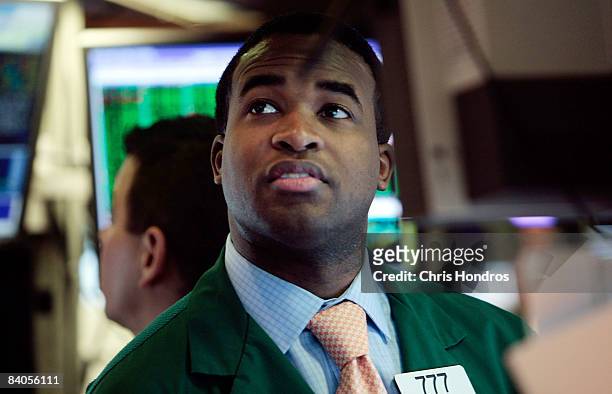 Financial professional looks up at a computer monitor on the floor of the New York Stock Exchange soon after the Federal Reserve's rate cut December...