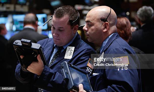 Financial professionals look over a hand-held computer on the floor of the New York Stock Exchange at the end of the trading day December 16, 2008 in...