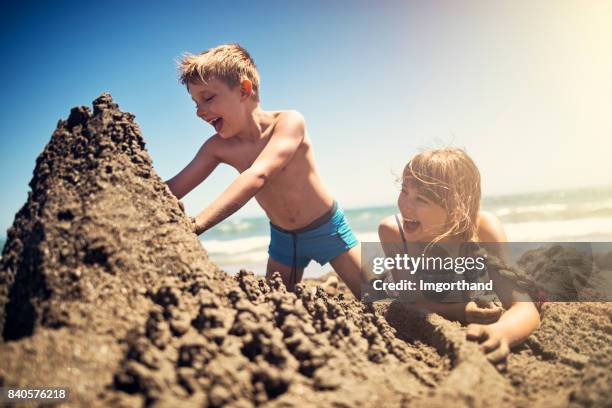 broer en zus bouw een zandkasteel op strand - zandkasteel stockfoto's en -beelden