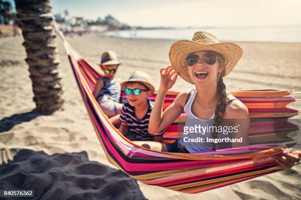 kinderen met plezier op hangmat op strand - spanje stockfoto's en -beelden