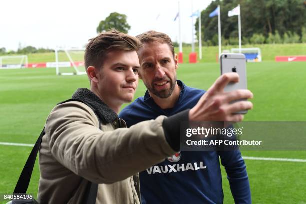 England's manager Gareth Southgate poses for a "selfie" photograph following a training session at St George's Park in Burton-on-Trent on August 29...