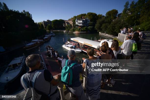 Bystanders wait for the arrival of taxi-boats transporting celebrities on the eve of the opening ceremony of the 74th Venice Film Festival on August...