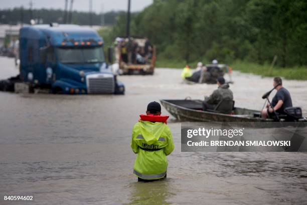 People make their way through a flooded street during the aftermath of Hurricane Harvey on August 29, 2017 in Houston, Texas. - Floodwaters have...