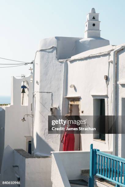 woman in red dress leans against the doorframe of a traditional greek house, in bright sunlight, kastro village, sifnos, cyclades islands, greece - sifnos ストックフォトと画像
