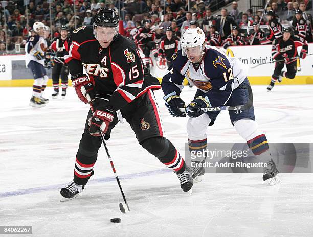 Dany Heatley of the Ottawa Senators stickhandles the puck against Todd White of the Atlanta Thrashers at Scotiabank Place on December 16, 2008 in...