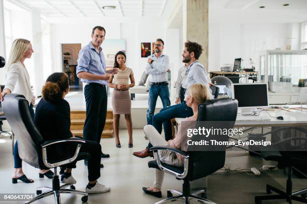 group of colleagues holding meeting in modern office space - serious business talk stock pictures, royalty-free photos & images