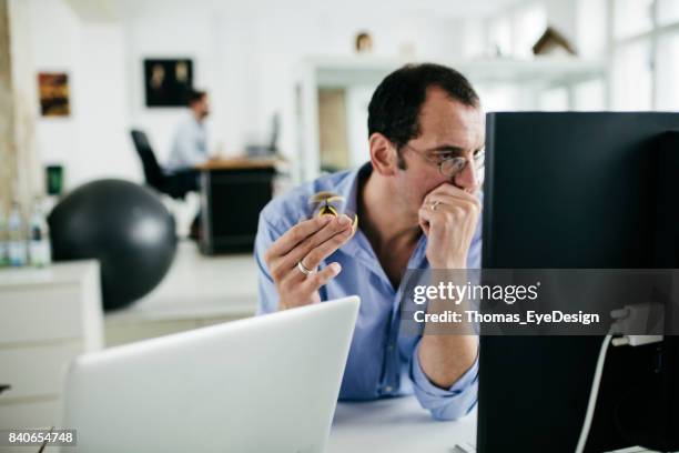 büroangestellte, die am computer arbeiten, während fidget spinner mit - fidget spinner stock-fotos und bilder