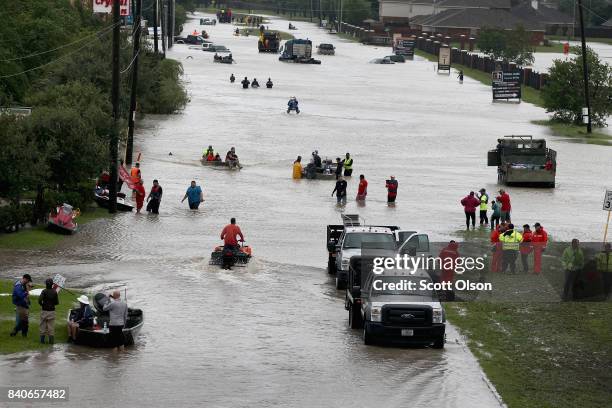 People make their way out of a flooded neighborhood after it was inundated with rain water following Hurricane Harvey on August 29, 2017 in Houston,...