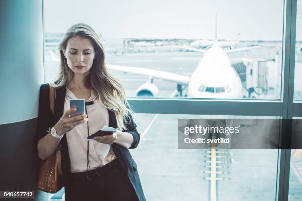 checking her boarding schedule - airport smartphone stock pictures, royalty-free photos & images