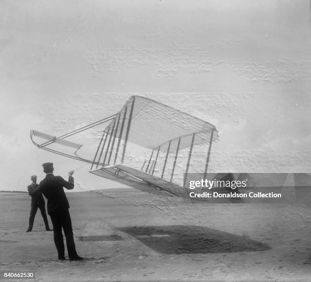 Glider being flown as a kite, Wilbur at left side, Orville at right; Kitty Hawk, North Carolina in 1901.