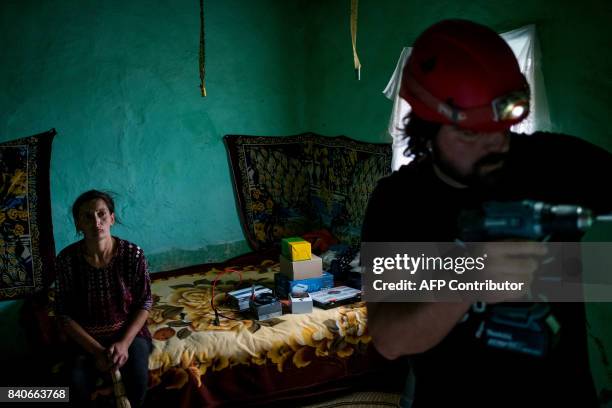 Woman watches while Iulian Angheluta, the founder of an NGO that tries to bring electricity to remote villages, prepares to install a solar panel on...