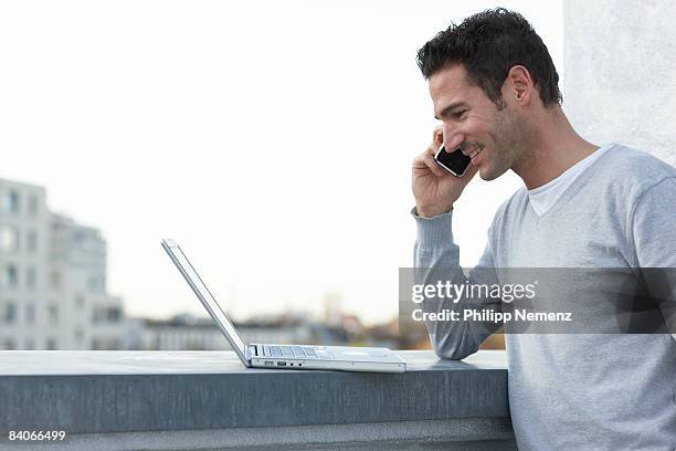 man with cellphone on rooftop - philipp nemenz foto e immagini stock