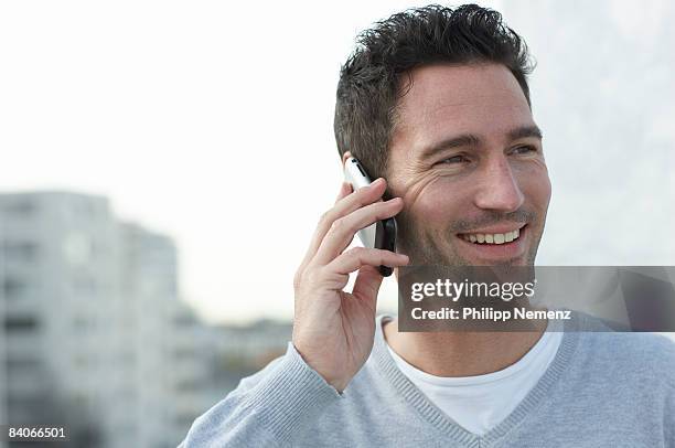 man with cellphone on rooftop - philipp nemenz stock-fotos und bilder