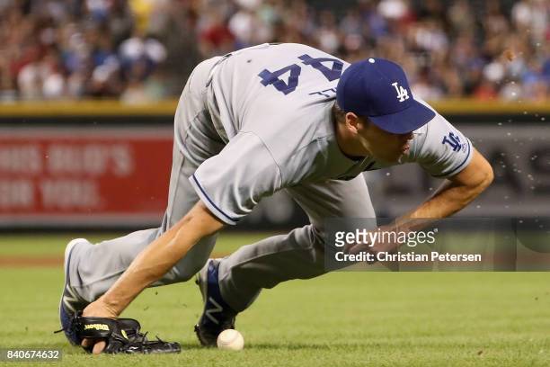 Starting pitcher Rich Hill of the Los Angeles Dodgers falls to the grass after being hit by a line drive single from Paul Goldschmidt of the Arizona...