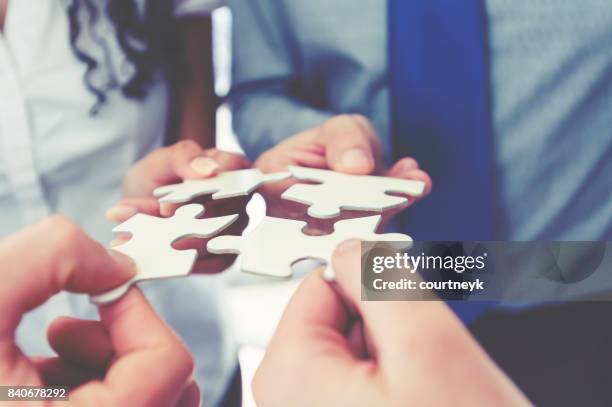 gruppe von geschäftsleuten, die halten ein jigsaw puzzle-teile. - konformität stock-fotos und bilder