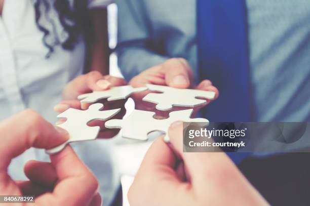 group of business people holding a jigsaw puzzle pieces. - business agreement stock pictures, royalty-free photos & images