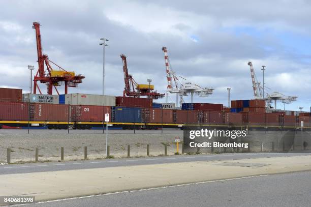 Shipping containers sit on well cars and near gantry cranes at the Port of Fremantle, Western Australia, Australia, on Saturday, Aug. 5, 2017....