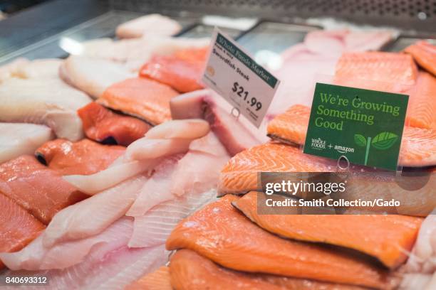 Signage on a display of fresh salmon at the Whole Foods Market store in Lafayette, California reading "Whole Foods Market and Amazon, New Lower...