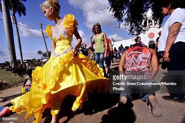 Cuban girl, dressed in the traditional Quince dress to celebrate the 15th birthday, walks amongst pilgrims trying to reach the Iglesia del Rincon...