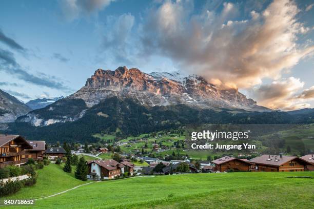 grindelwald village by bernese oberland against sky at swiss alps - berner alpen stock-fotos und bilder