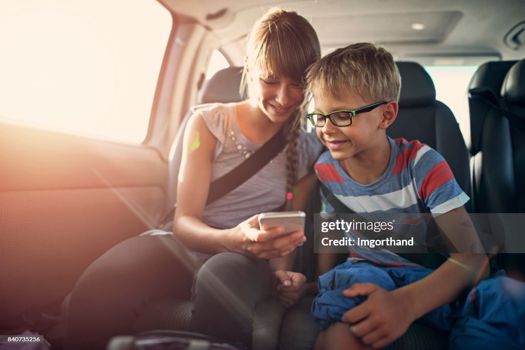 Kids playing smartphone during a road trip