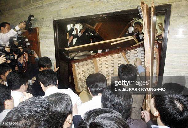 South Korean opposition party members tear down the door of a parliamentary committee room barricaded by ruling party legislators in Seoul on...