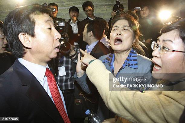 Two female legislators from South Korea's ruling Grand National Party shout insults at an opposition party legislator outside a parliamentary...