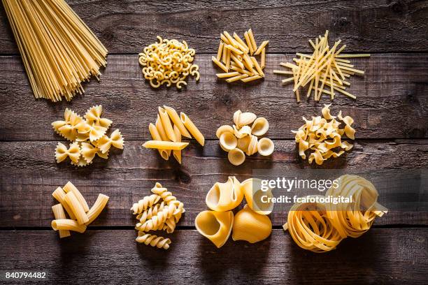 different types of italian pasta on rustic wooden table - massa-não-cozinhada imagens e fotografias de stock