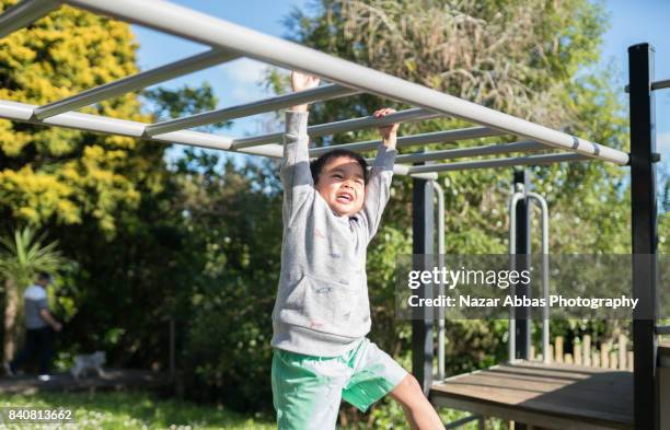 kid on monkey bar enjoying in playground. - monkey bars stock pictures, royalty-free photos & images