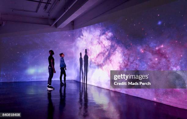 couple looking at large scale projected image of space - purple stock pictures, royalty-free photos & images