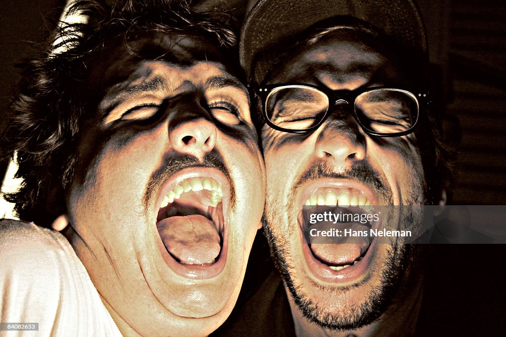 Two young men screaming under a flash light