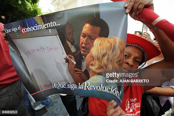 Supporter of Venezuelan President Chavez holds a poster with his portrait and the legend "Let Knowledge to Continue..." and "Go On Revolution!"...