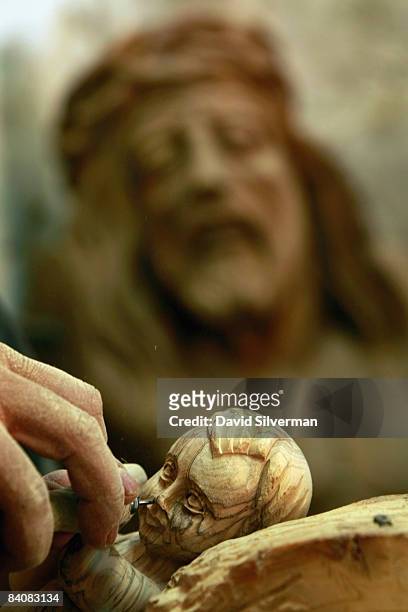 Palestinian craftsman Adel Daroud carves an olive wood effigy of the infant Jesus as a larger effigy of Jesus with a crown of thorns seems to look on...