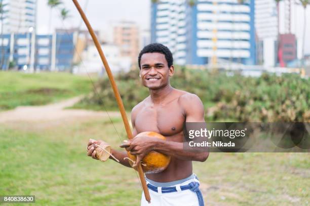 brazilian man playing capoiera music instrument, berimbau - berimbau stock pictures, royalty-free photos & images