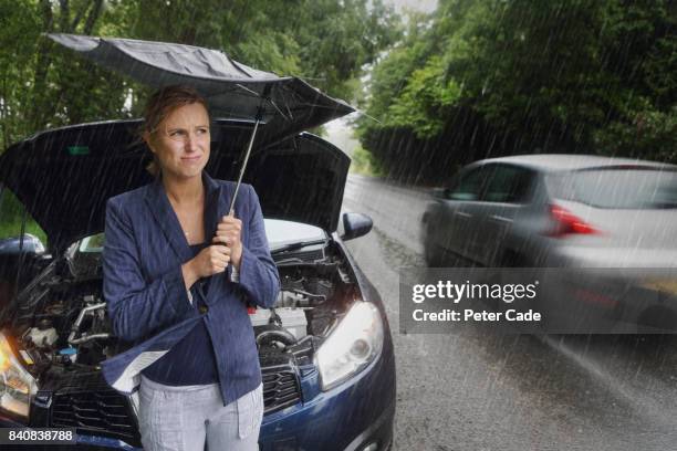 woman on side of road with broken down car in the rain - broken umbrella stockfoto's en -beelden