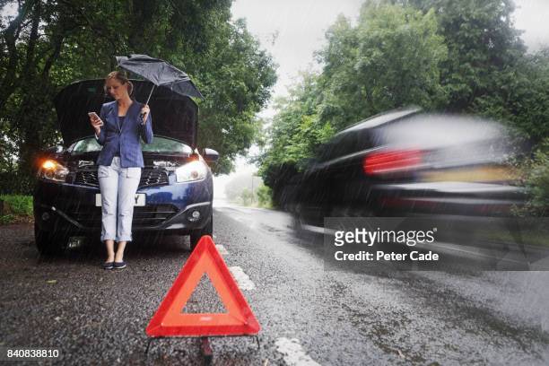 woman on side of road with broken down car in the rain - vehicle breakdown foto e immagini stock
