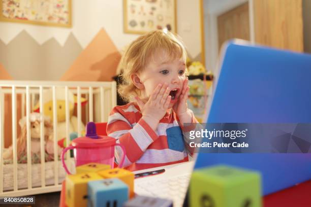 toddler in bedroom working on laptop, looking worried - mistake stockfoto's en -beelden