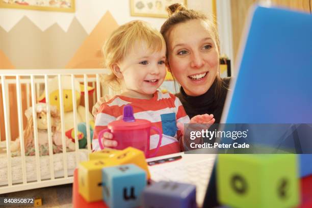 toddler in bedroom looking at on laptop with mother - family with one child mother bonding family adult daughter focus on background leisure stock-fotos und bilder