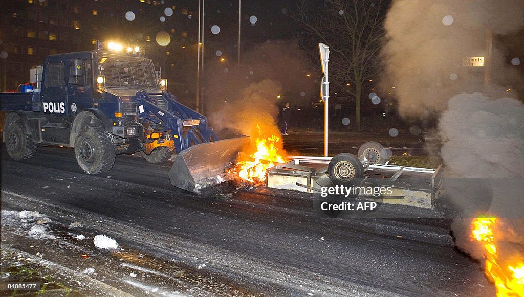 Policemen use a Unimog vehicle to clear